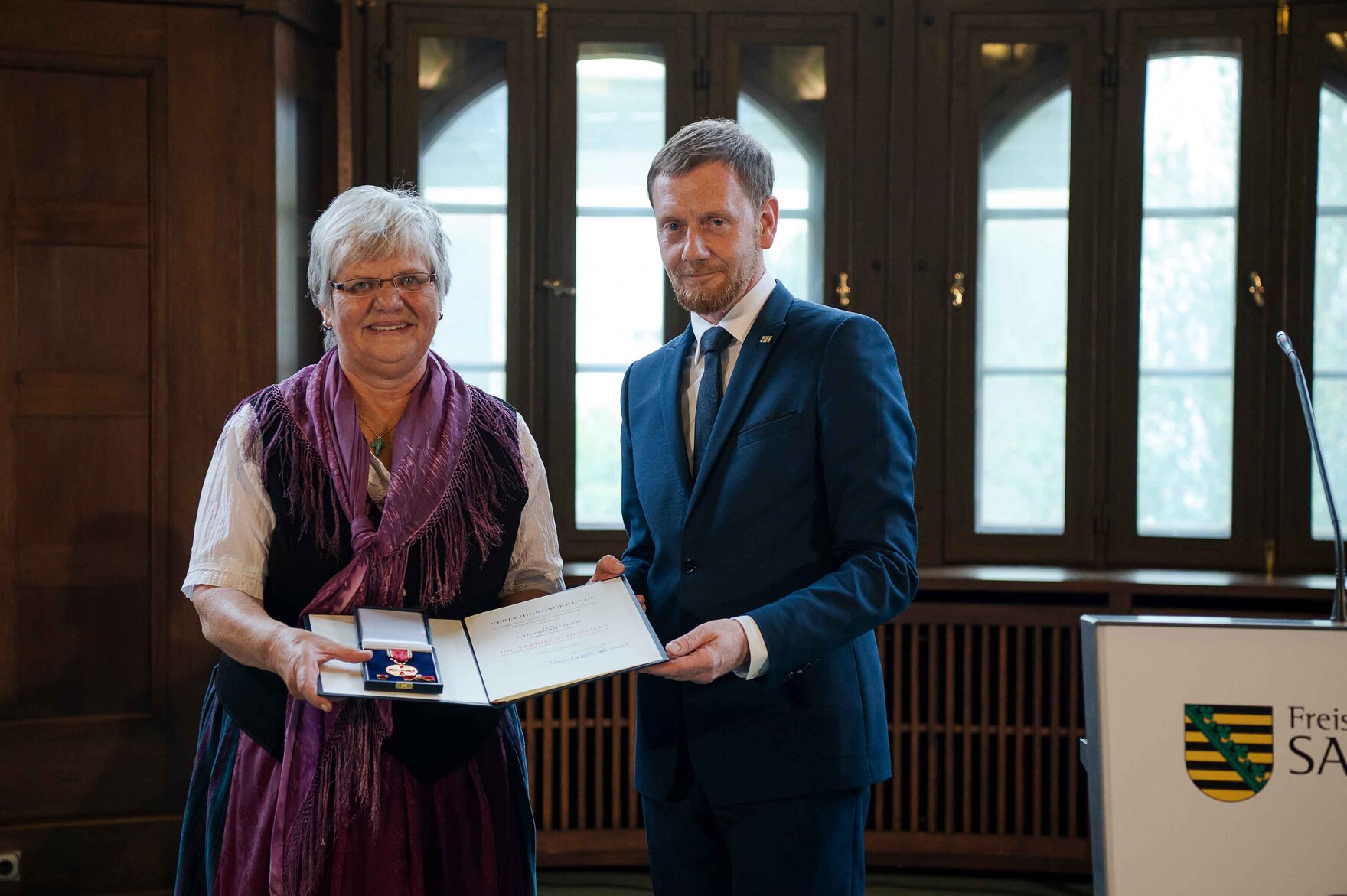 Ein Mann und eine Frau stehen vor einer Wand mit Fenstern. 