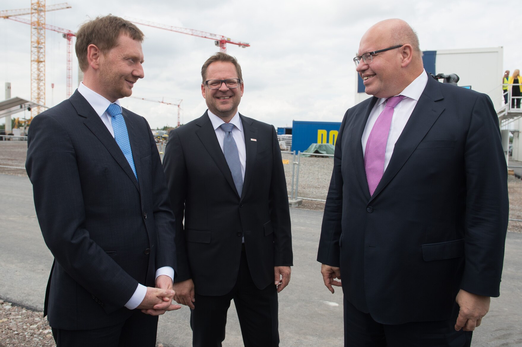 Drei Herren stehen auf einer Baustelle und unterhalten sich.