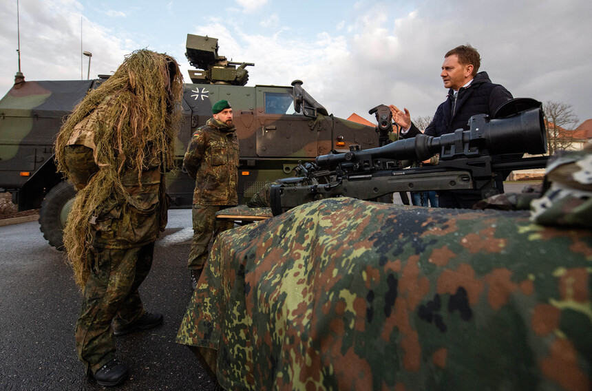 Soldatewn zeigen einem Mann einen Schützenpanzer.
