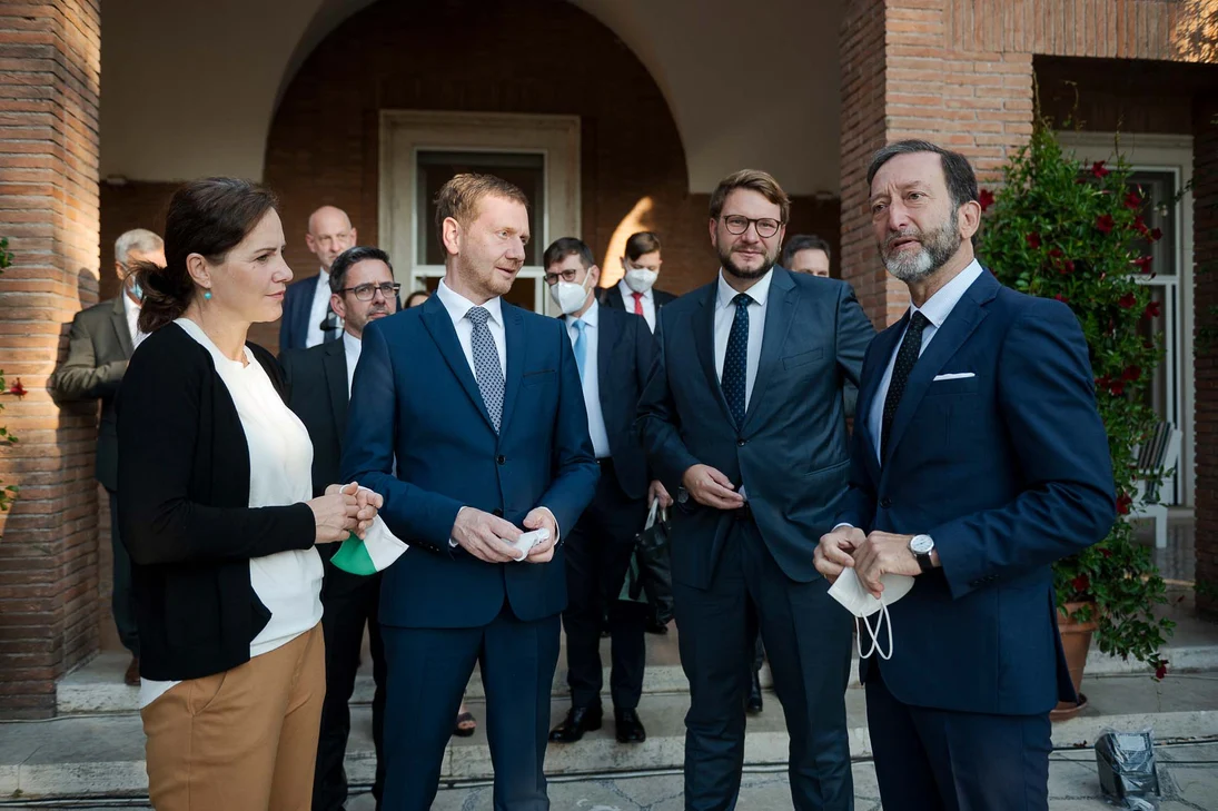 Männer und Frauen unterhalten sich vor einem Gebäude.