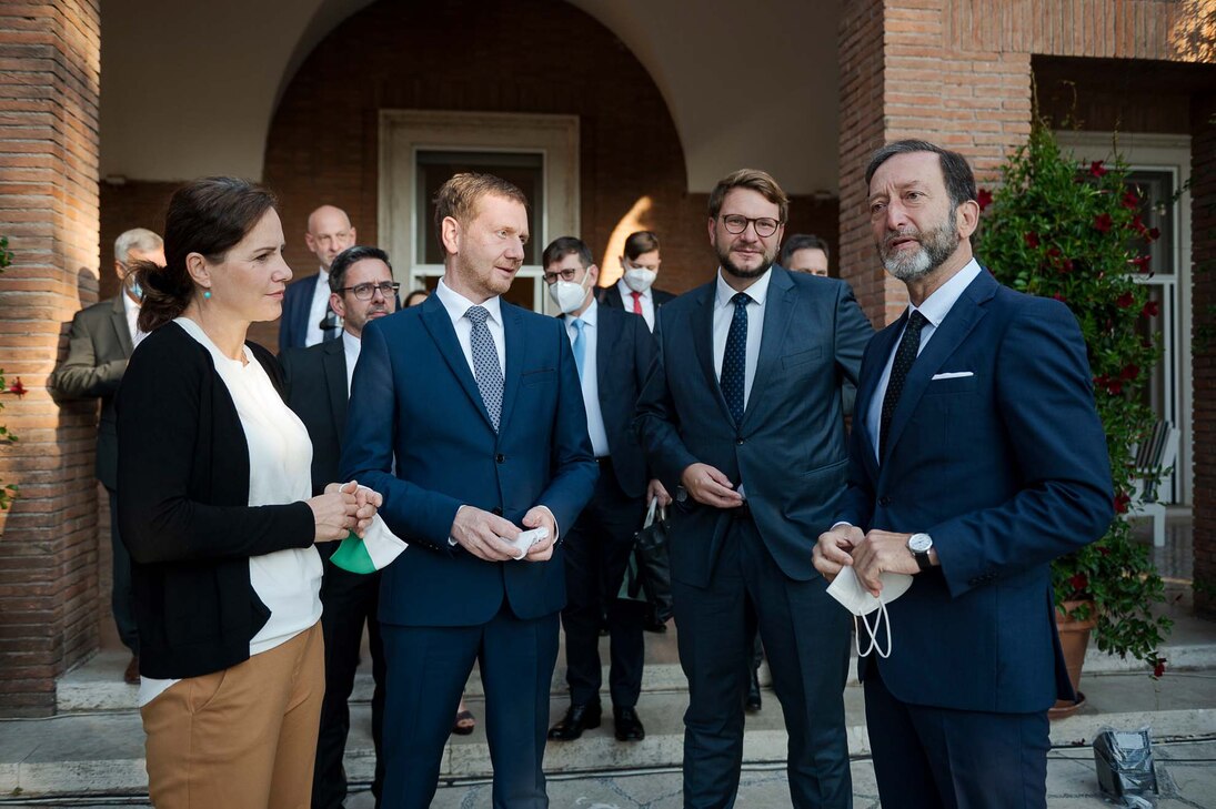 Männer und Frauen unterhalten sich vor einem Gebäude.