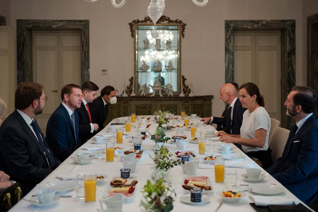 Männer und Frauen unterhalten sich an einem Tisch.