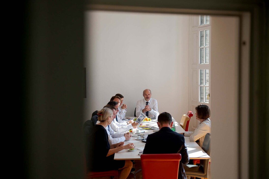 An einem Tisch sitzen Männer und Frauen, die sich unterhalten.