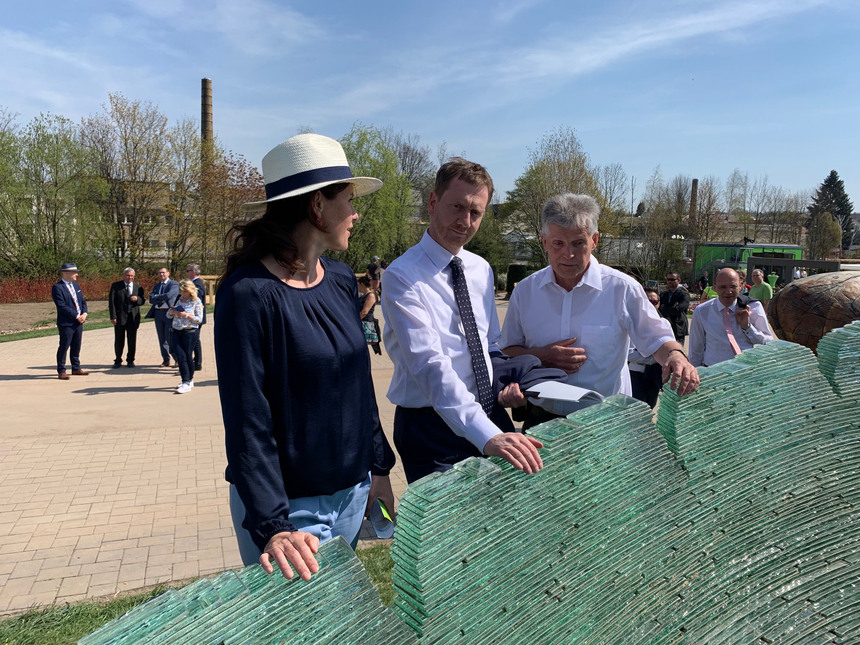 Zwei Männer und eine Frau stehen vor einer Gartenausstellung.