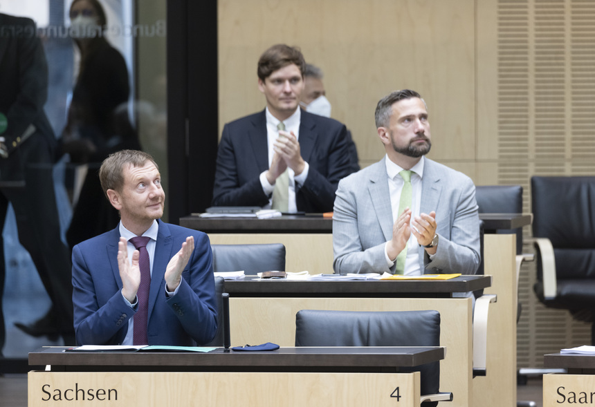 Drei Männer sitzen in einem Sitzungssaal