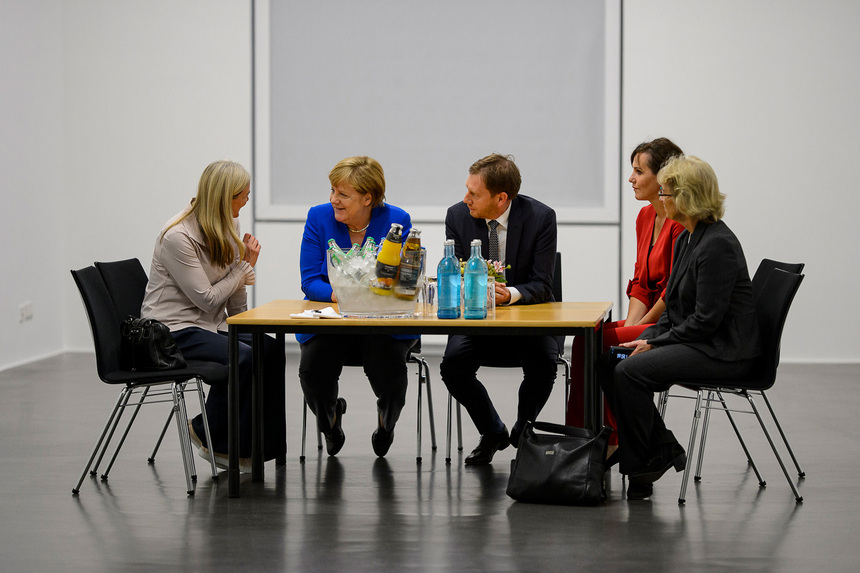 Männer und FRauen sitzen an einem Tisch.