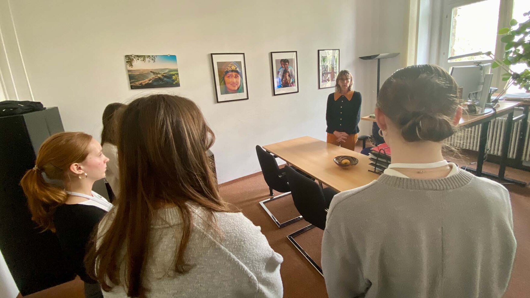 Eine Frau steht in einem Büro vor vier Jugendlichen und spricht mit ihnen.