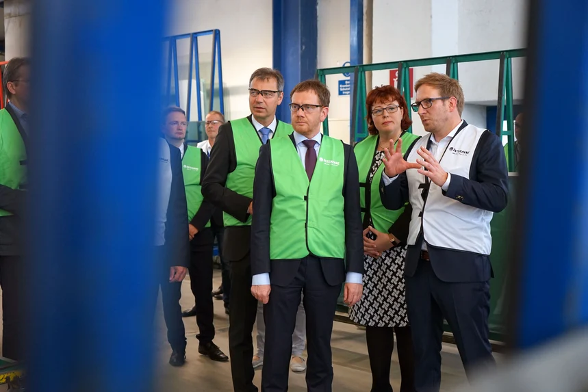 Mehrere Menschen stehen in einer Werkhalle und unterhalten sich.