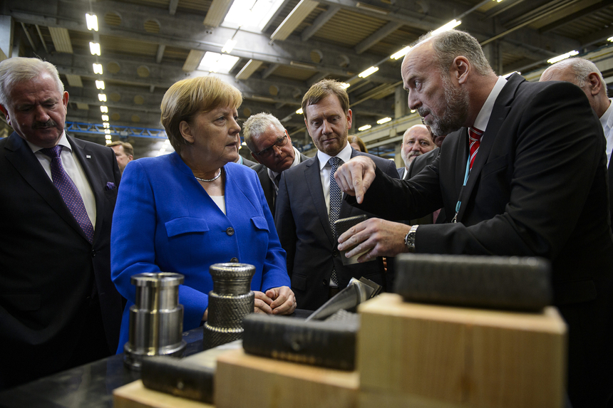 Ein Mann erklärt einer Frau und mehreren Männern ein technisches Teil.