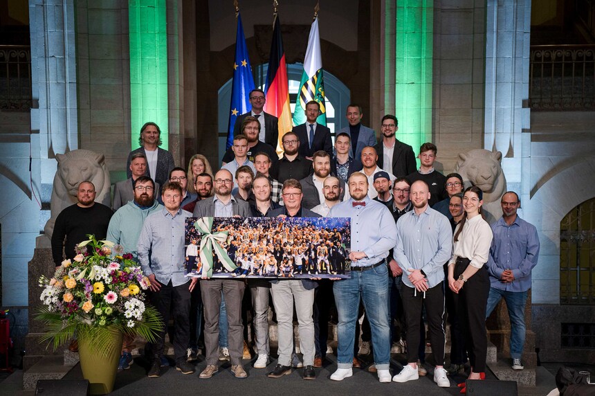 Mehrere Menschen stehen für ein Foto auf einer Treppe in einem alten Gebäude.