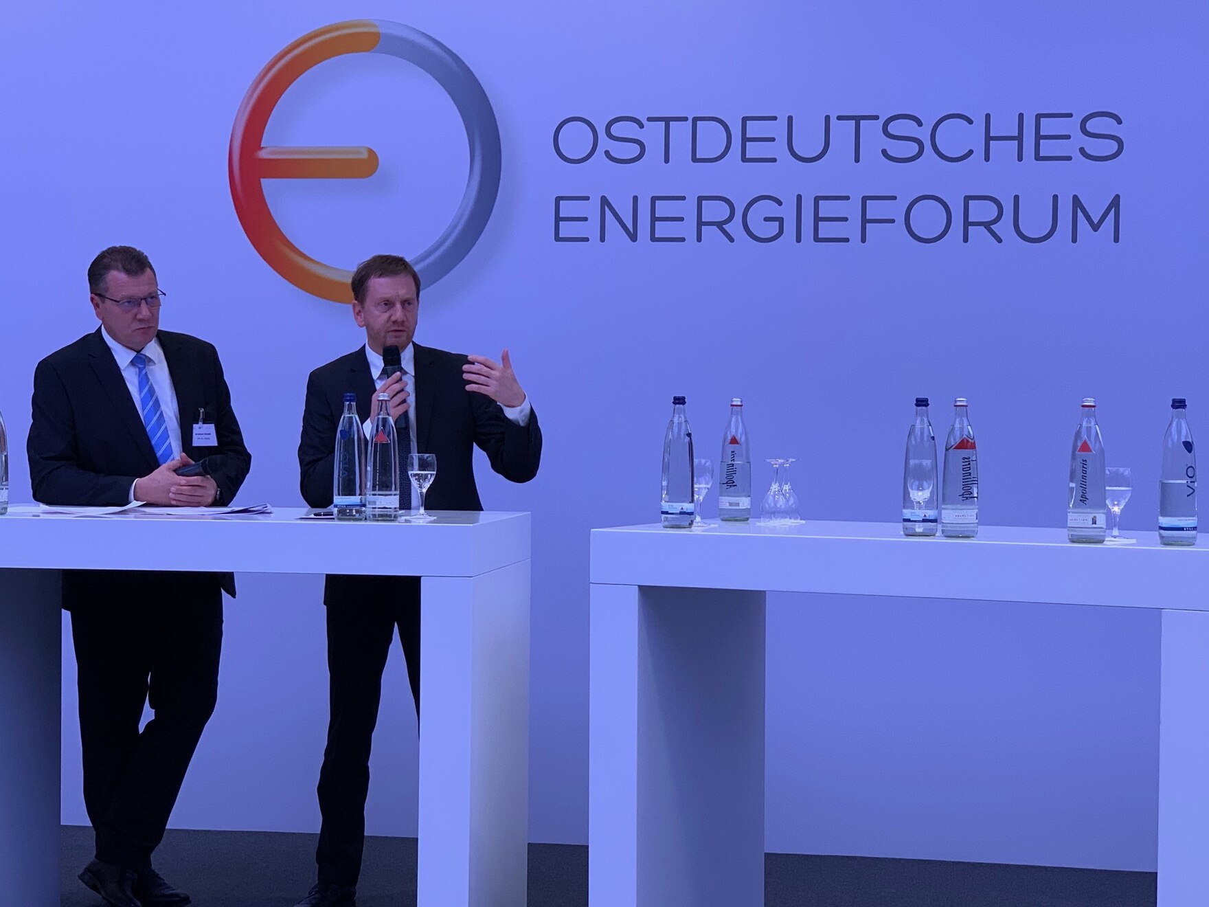 Zwei Männer stehen vor einer Wand auf der »Ostdeutsches Energieforum« steht.