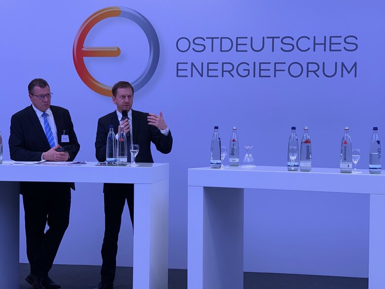 Zwei Männer stehen vor einer Wand auf der »Ostdeutsches Energieforum« steht.