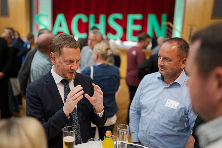 Mehrere Menschen sind an einem Stehtisch miteinander im Gespräch.