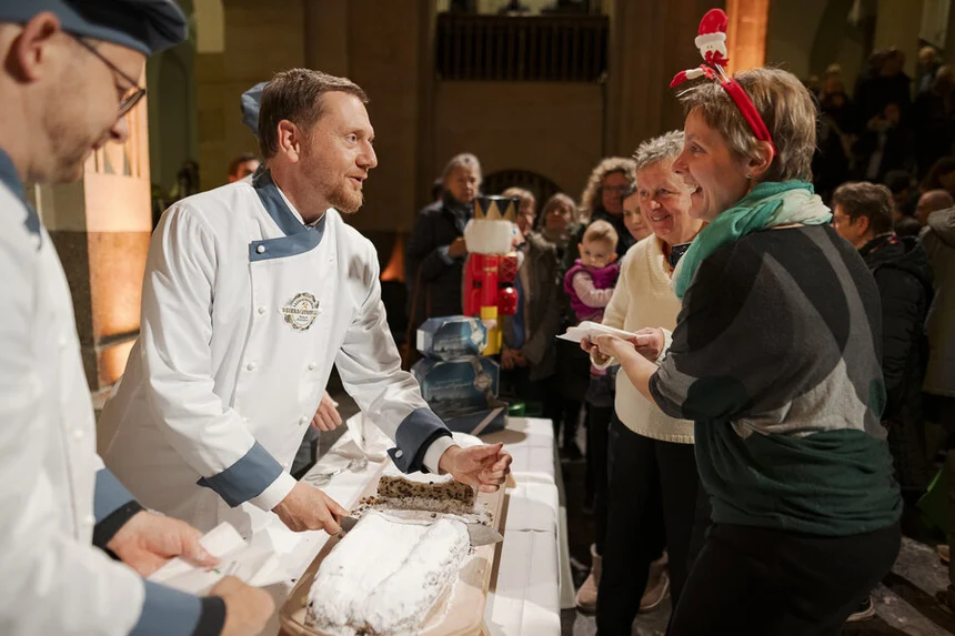 Ein Mann schneidet einen Stollen an und unterhält sich mit einer Frau,