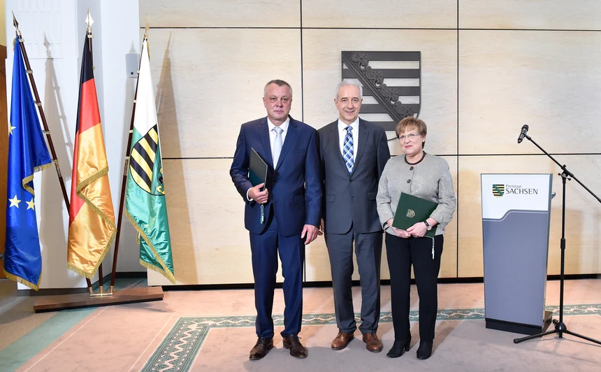 Zwei Männer und eine Frau posieren für Pressefotos.