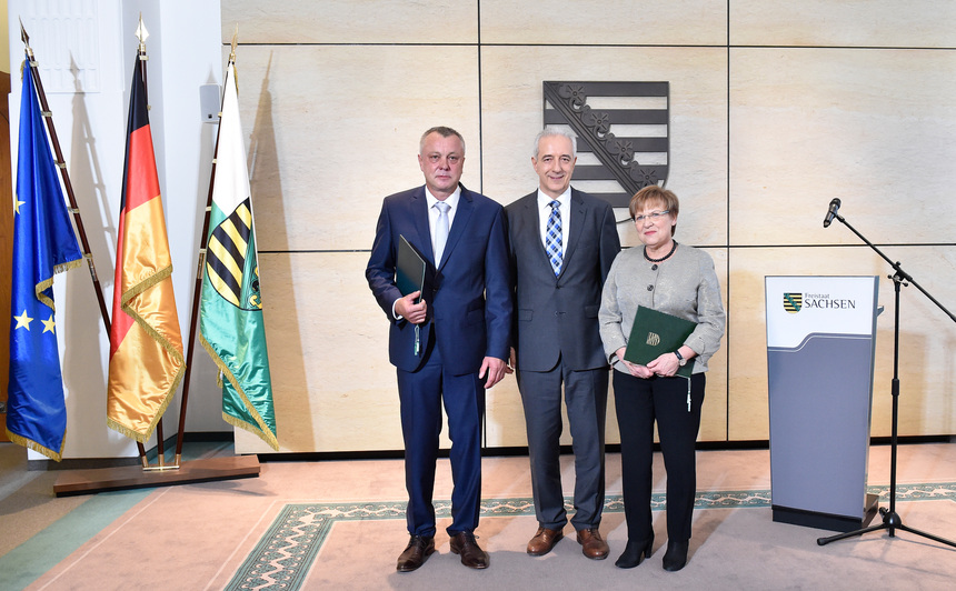 Zwei Männer und eine Frau posieren für Pressefotos.