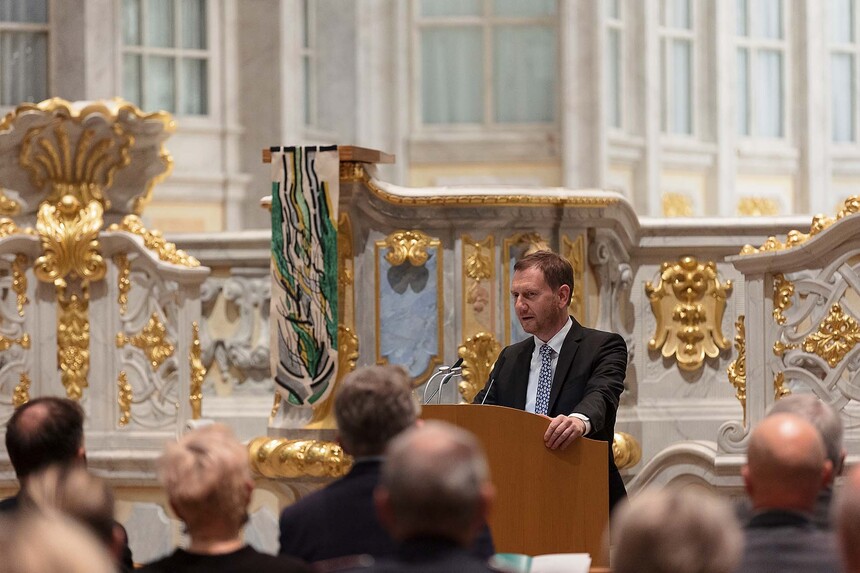 Ein Mann steht an einem Rednerpult vor einem Kirchenaltar.