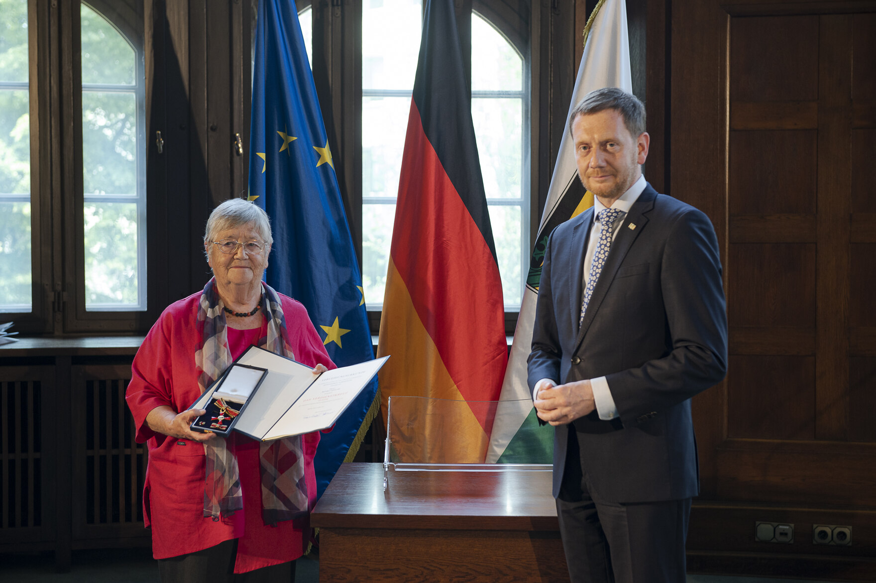 Eine Frau hält eine Urkunde in der Hand. Neben ihr steht ein Mann.