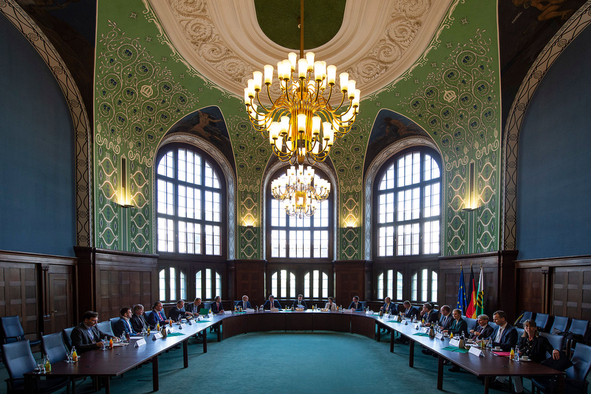 Männer und Frauen sitzen in einem großen Saal.