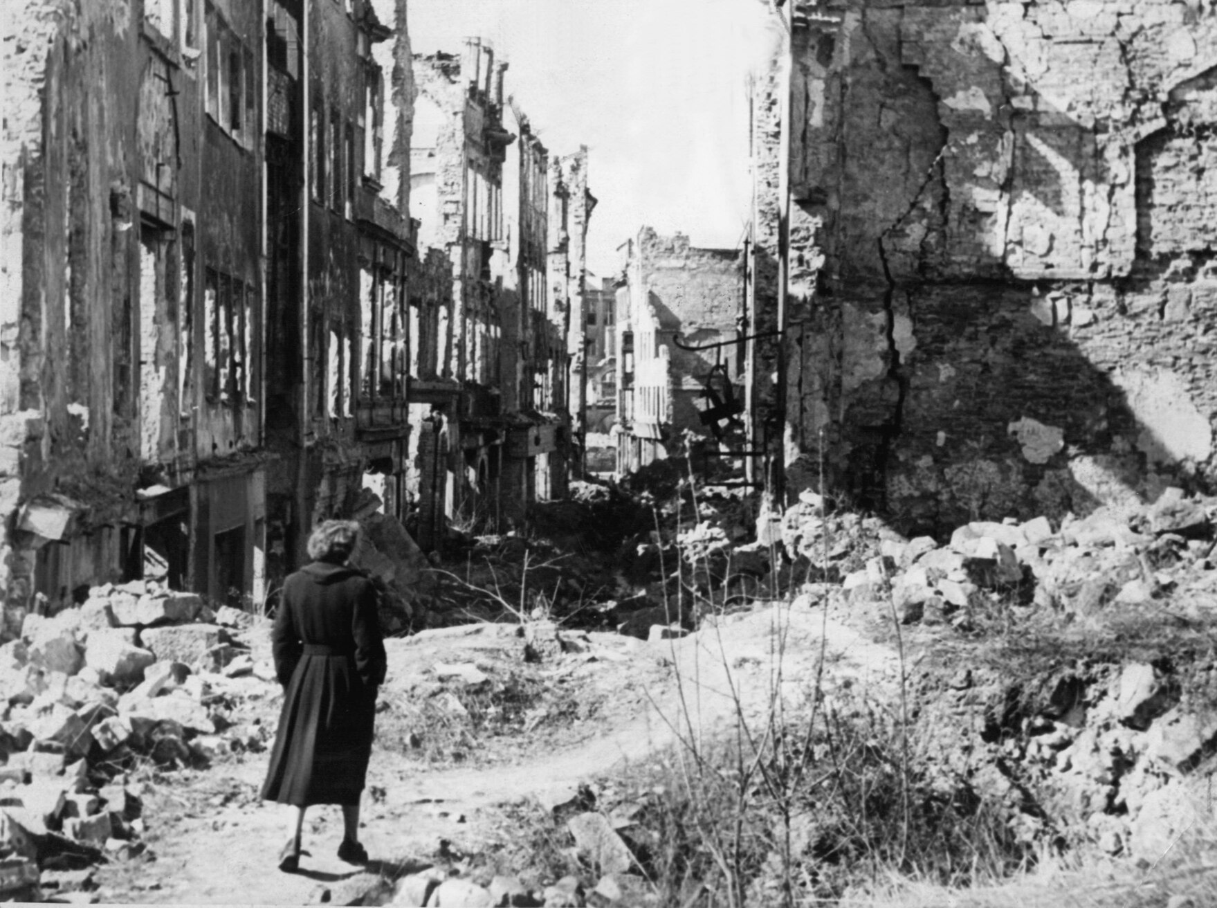 Eine Frau geht durch eine zerstörte Stadt.