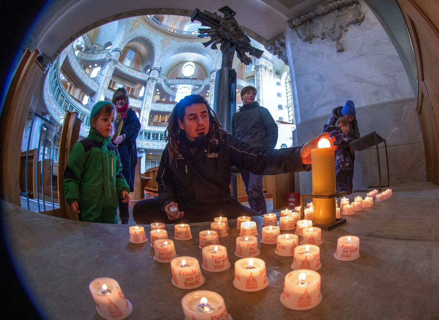 Ein Mann und ein kleiner Junge zünden Kerzen in einer Kirche an.