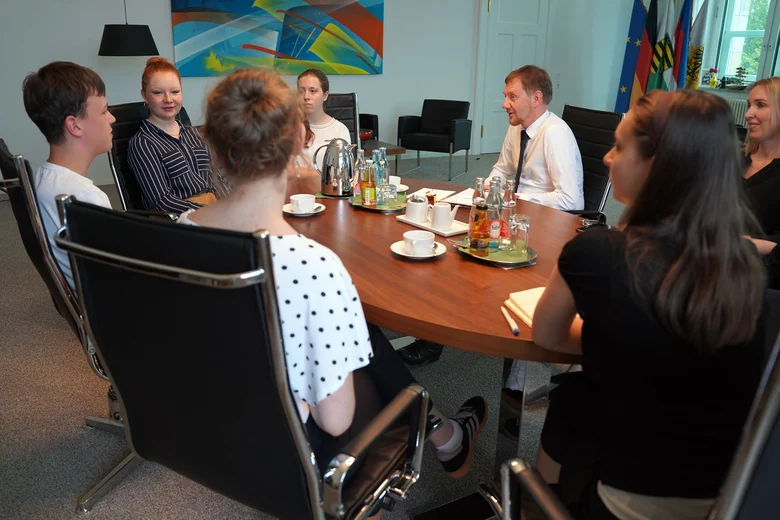 Mehrere Personen sitzen an einem ovalen Tisch in einem modernen Büro.