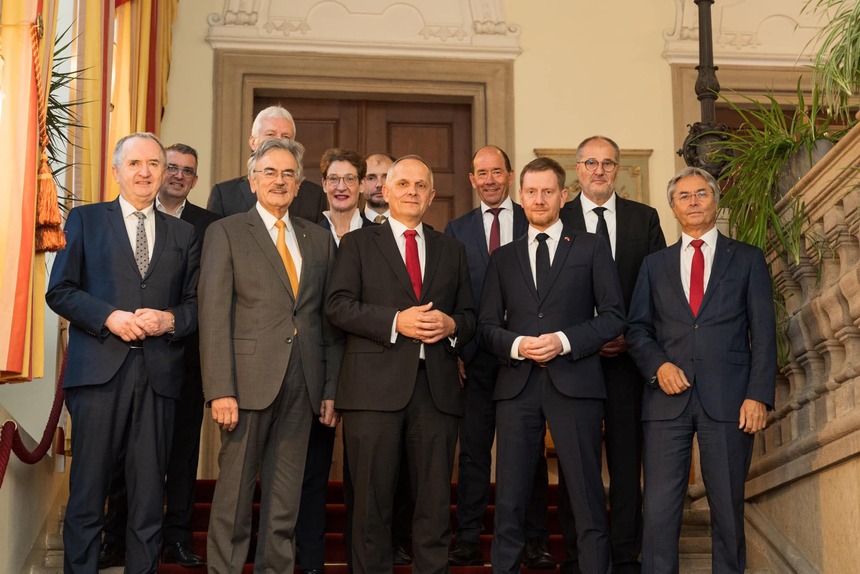 Männer und eine Frau stehen auf einer Treppe und posieren für ein Foto.