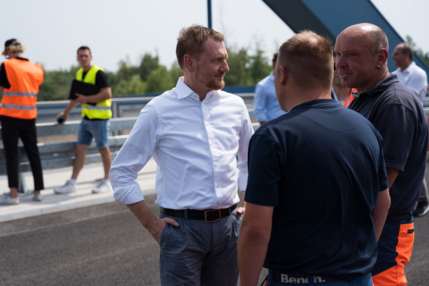 Männer unterhalten sich auf einer Autobahnbrücke.