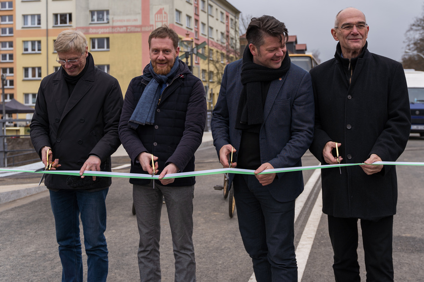 Männer durchtrennen ein Band mit einer Schere.