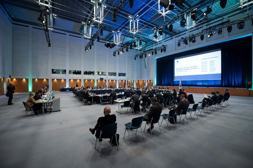 Männer und Frauen sitzen in einem großen Saal.