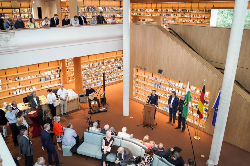 Männer und Frauen stehen in einer Bibliothek.