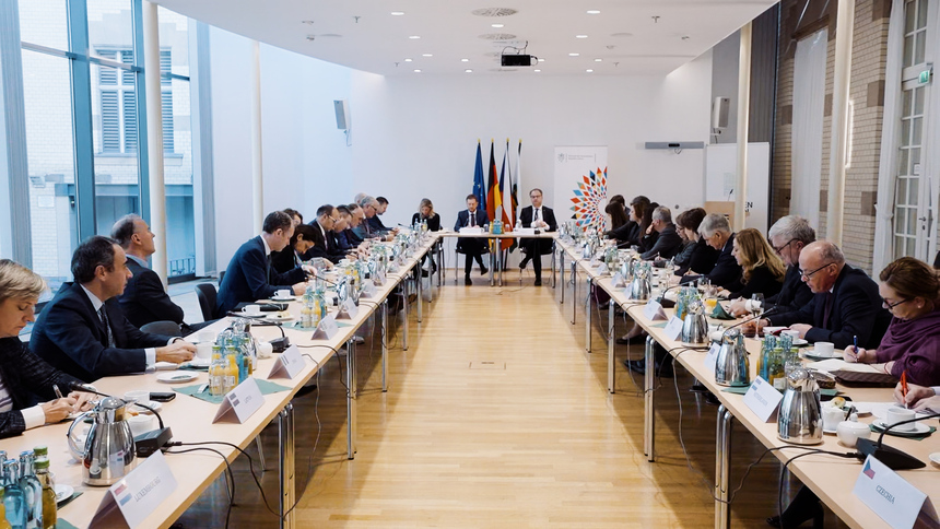 Männer und Frauen sitzen an einem Konferenztisch.