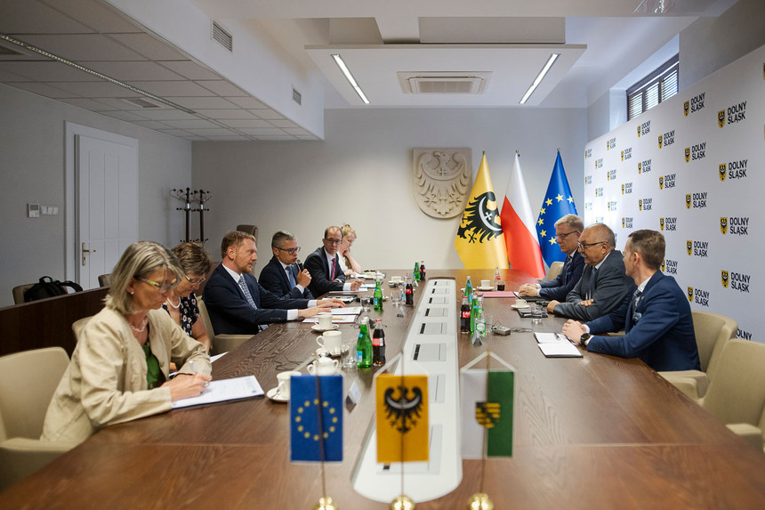 Männer und Frauen sitzen an einem Konferenztisch.