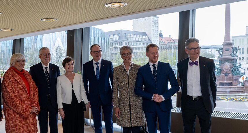 Männer und Frauen stehen in Reihe vor einem großen Panoramafenster.