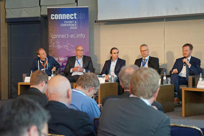 Männer sitzen auf einer Konferenz in einer Gesprächsrunde.