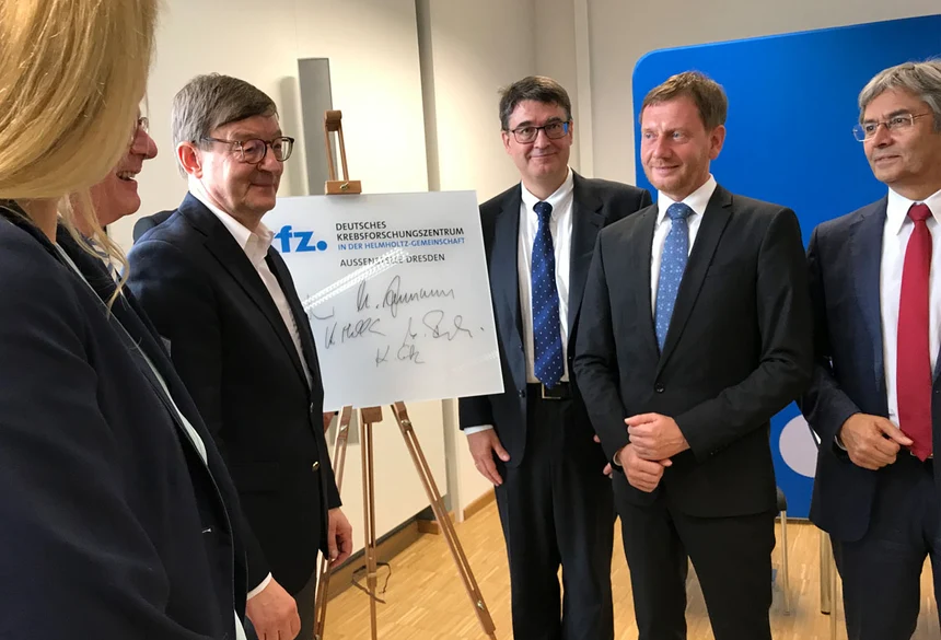 Männer stehen vor einer Tafel.