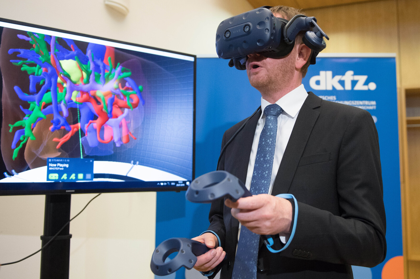 Ein Mann trägt eine VR-Brille und hält zwei Controller in der Hand.