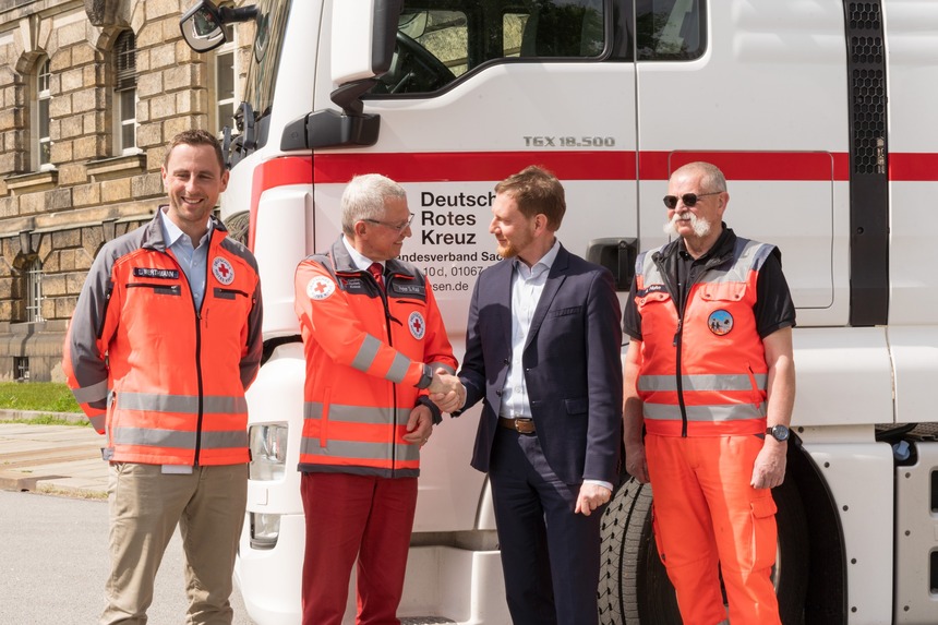 Männer stehen vor einem LKW. Ein Mann reicht dem anderen die Hand.