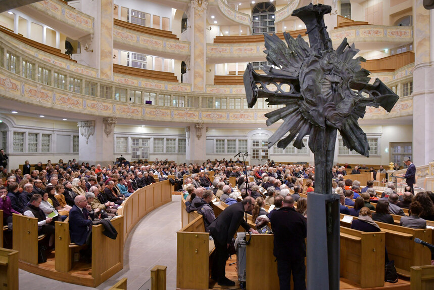 Eine Kirche in der Menschen sitzen und einem Redner zuhören.