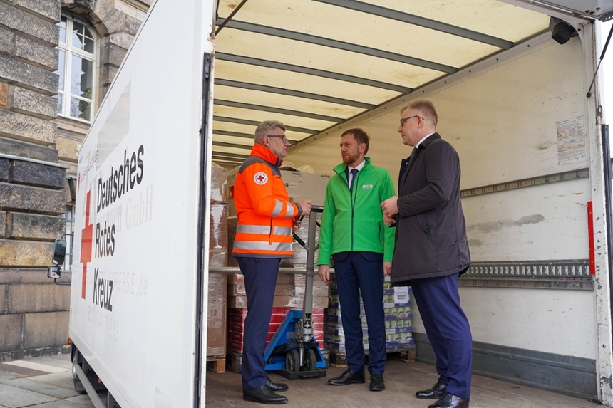 Drei Männer stehen im Laderaum eines LKW.