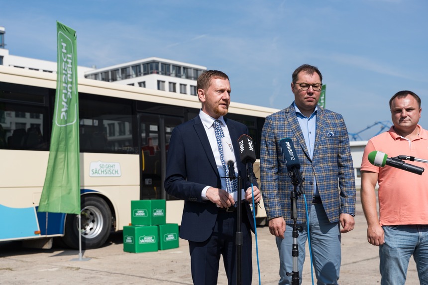 Drei Männer stehen vor einem Bus.