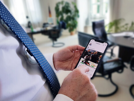 Ein Mann hält ein Smartphone in der Hand, auf dem die Instagram-App geöffnet ist.
