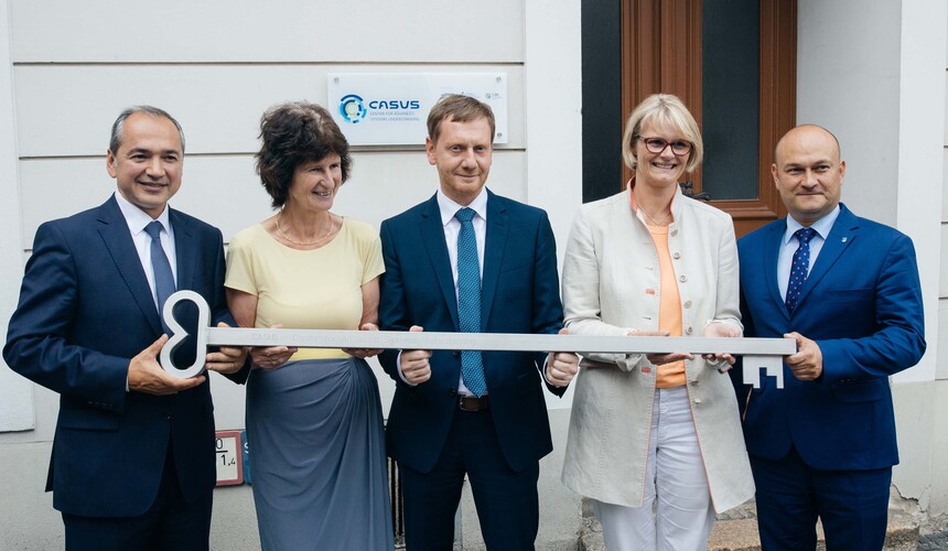 Männer und Frauen halten einen Schlüssel in der Hand.