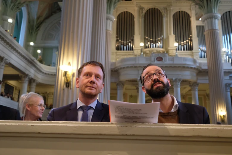 Zwei Männer sitzen auf einer Kirchenbank.