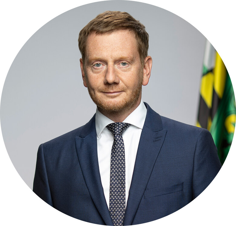 Ein Mann im Anzug, im Hintergrund die Sächsische Flagge