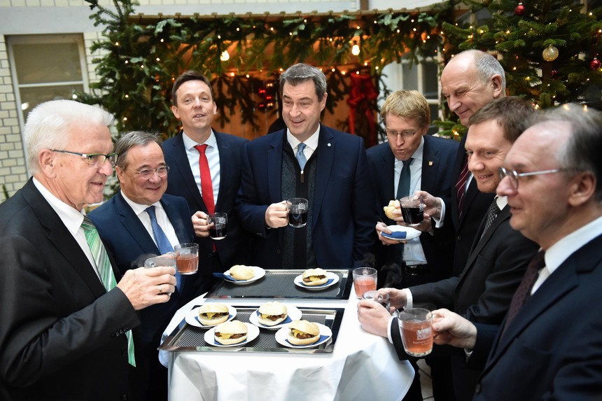 Männer stehen an einem Tisch und trinken Glühwein.