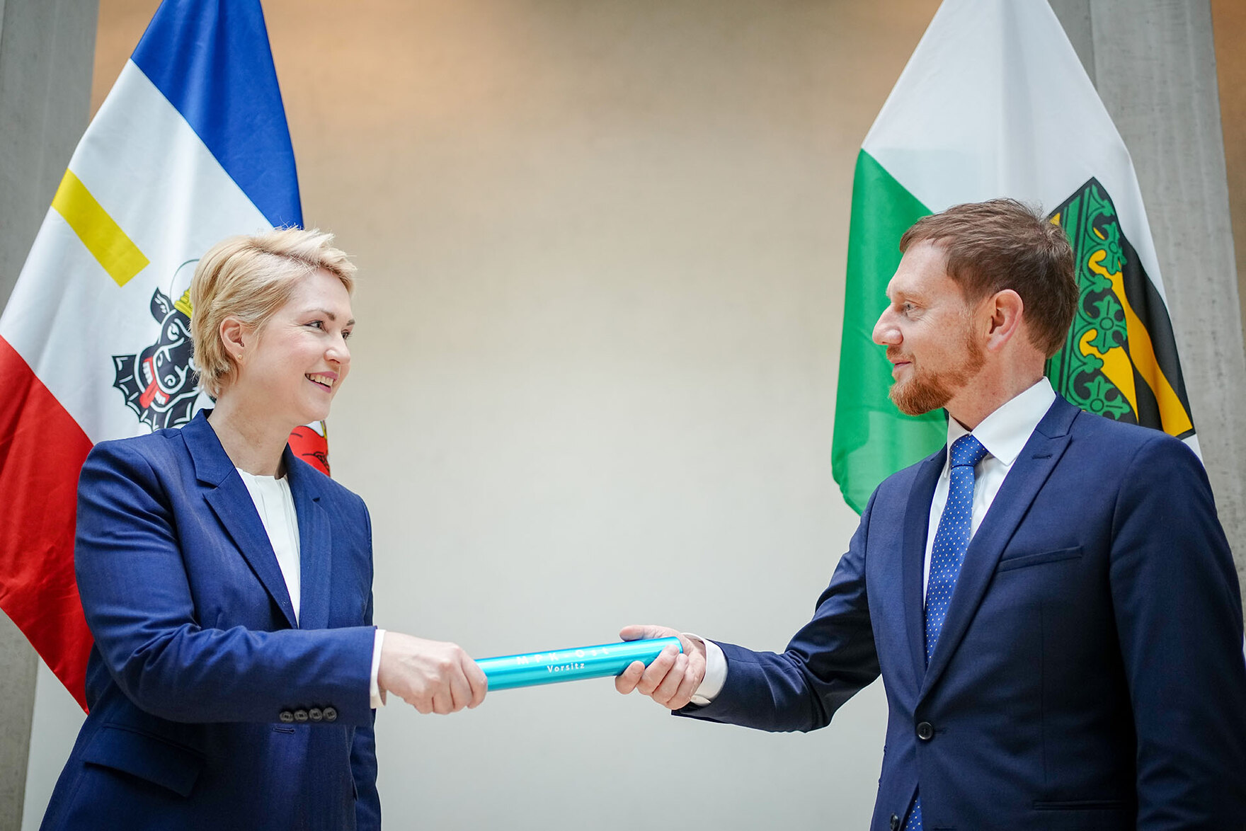 Eine Frau übergibt eine Staffel an einen Mann.