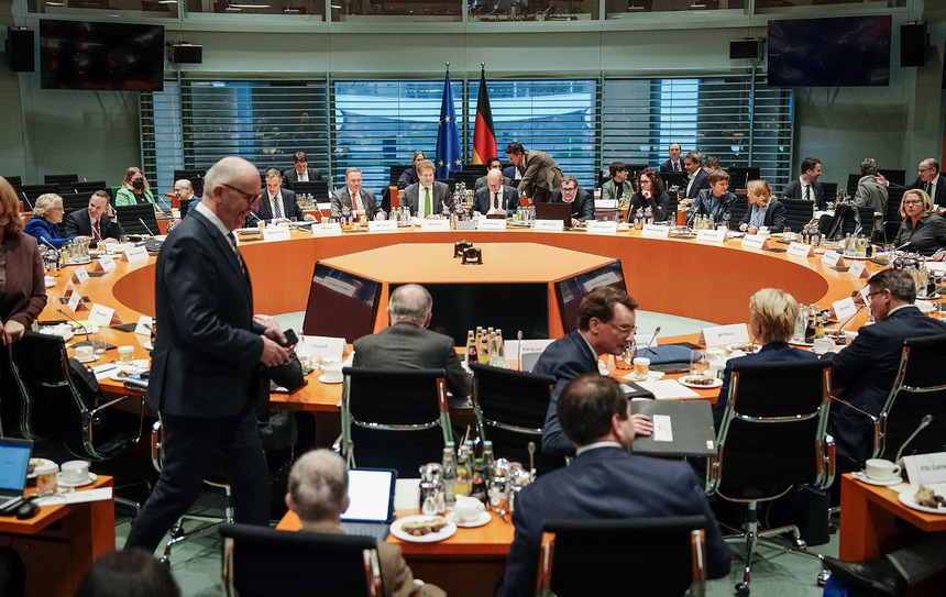 Männer und Frauen sitzen an einem runden Tisch.