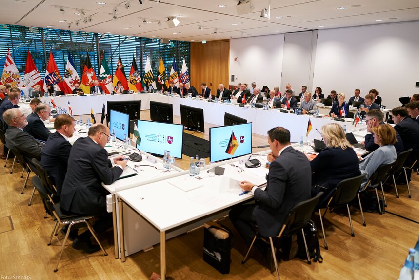 Männer und Frauen sitzen an einem Konferenztisch.