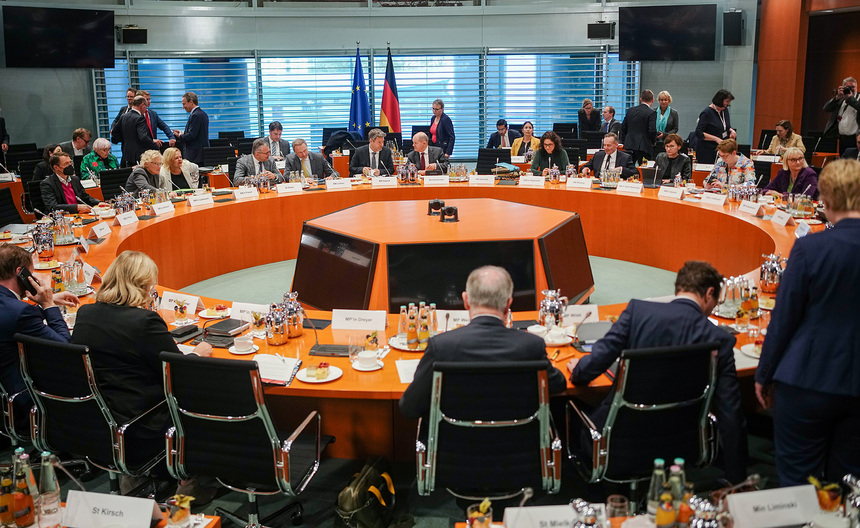 Männer und Frauen sitzen an einem runden Konferenztisch.